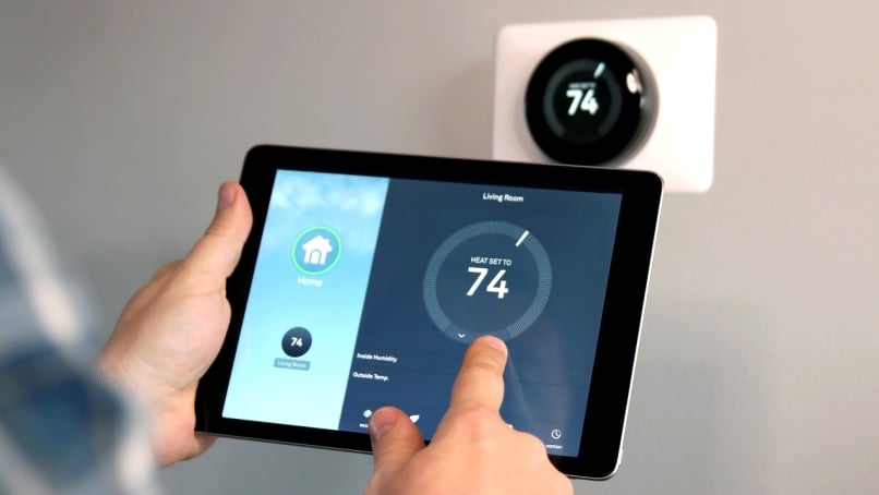 Man adjusting temperature using a tablet with smart home application in modern living room.