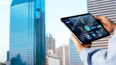 Engineer hands using digital tablet with building management software on blurred modern office building as background