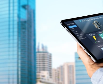 Engineer hands using digital tablet with building management software on blurred modern office building as background