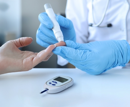 Doctor with gloves monitoring blood glucose by piercing patient's finger with lancet and using a blood glucose meter