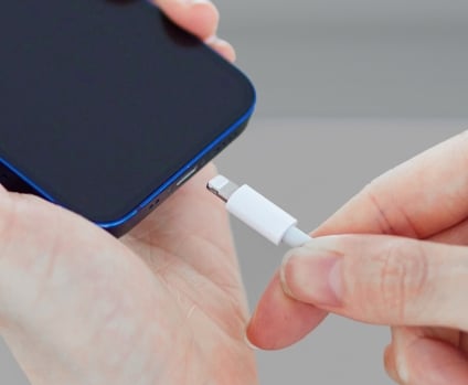 Hand plugging a usb charger cord into a smartphone